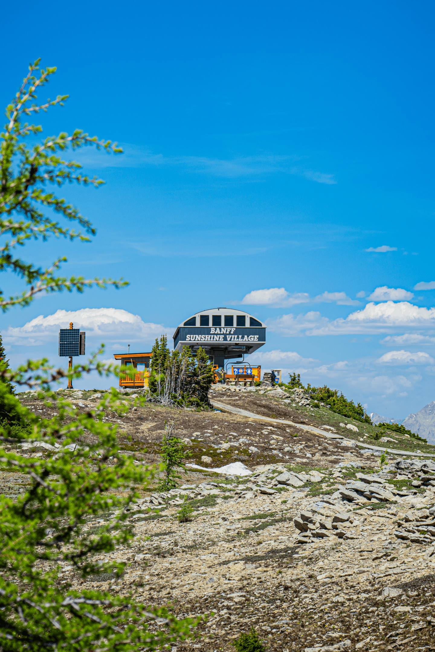 Modern glass building atop a rocky hill under a bright blue sky
