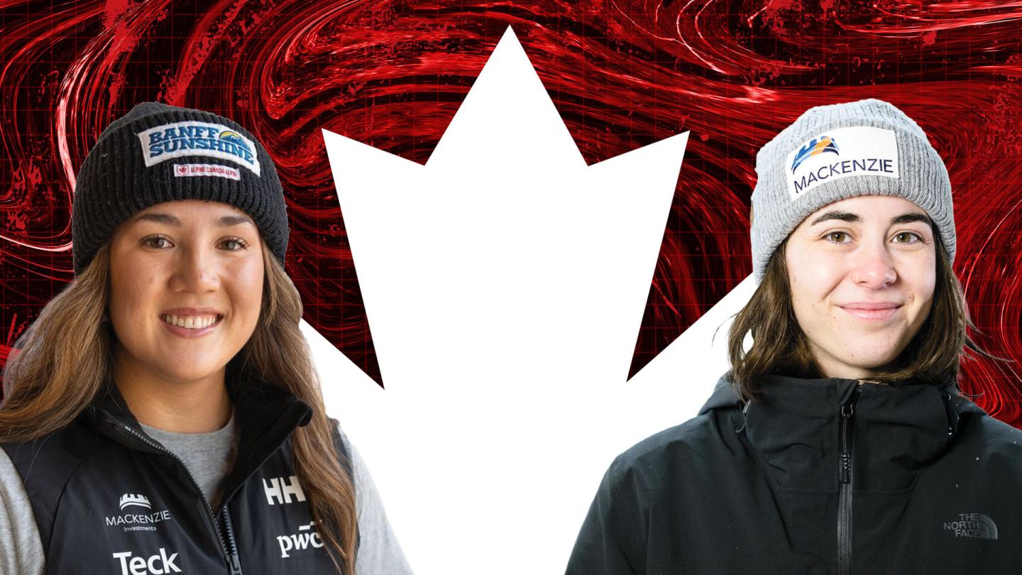 Two women in winter gear stand beside a large white maple leaf on a red background.