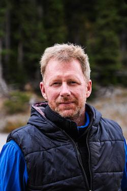 Portrait of a man in a black quilted vest outdoors.