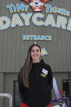 Woman standing beneath the Tiny Tigers Daycare entrance sign.