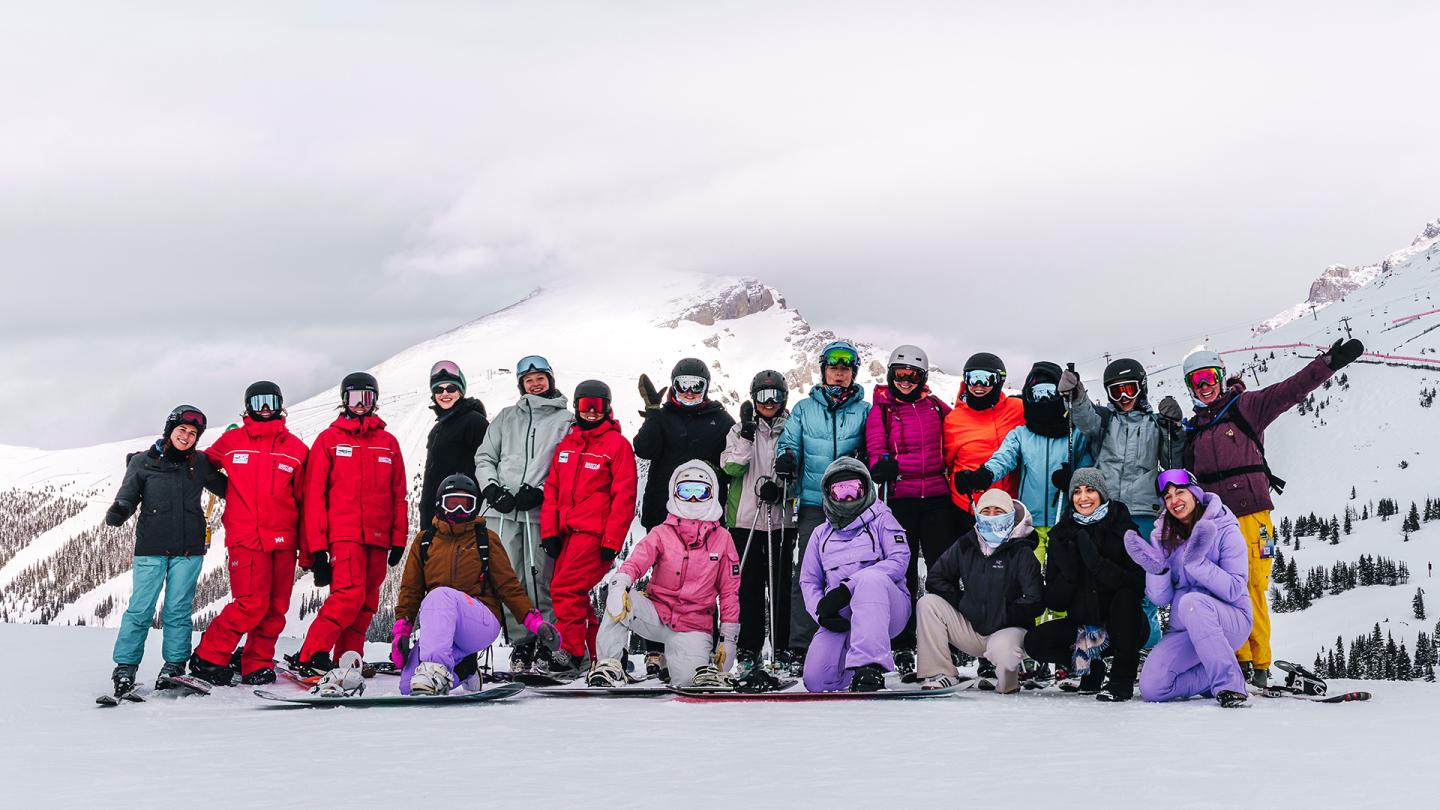 Group of skiers and snowboarders posing on a snowy mountain slope.